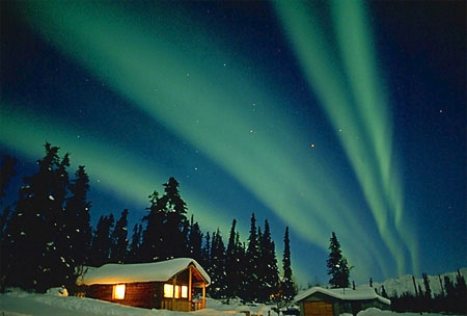 Aurora lights up sky over log cabin
